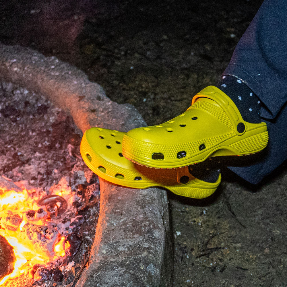 Yellow off-road clogs worn beside a campfire at night.