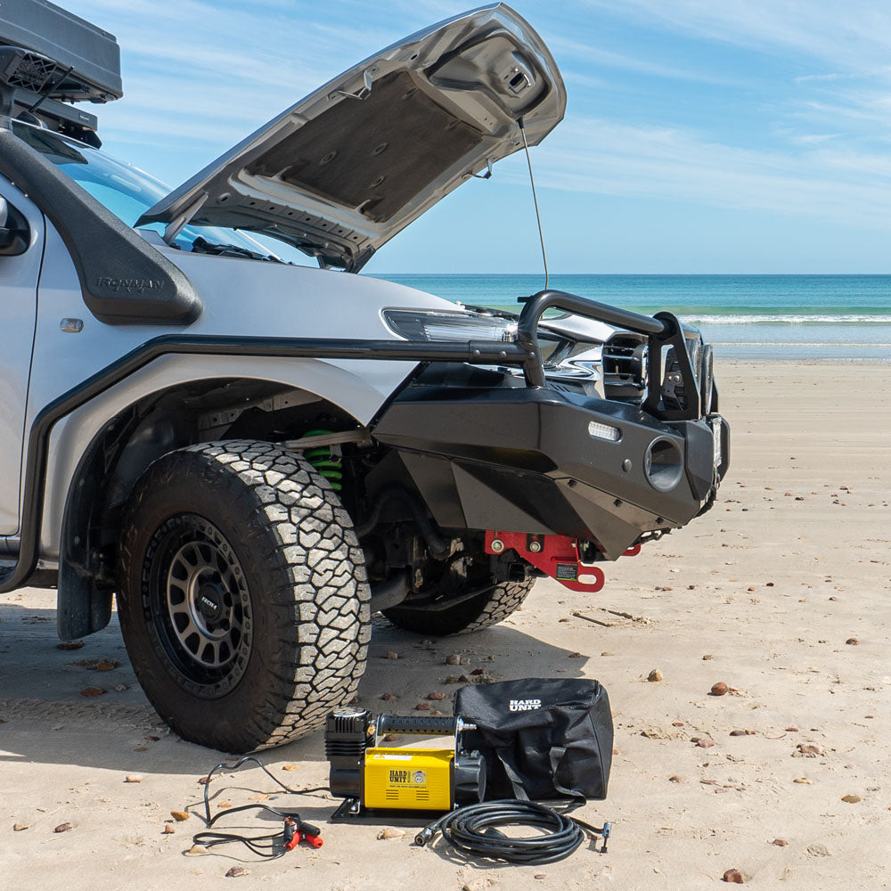 12V portable air compressor kit on beach, ideal for off-road tyre inflation and recovery.