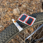 Cold patches kit with rubber cement and adhesive repair patches resting on rear wheel of a bicycle, ideal for fixing punctured bike tubes.
