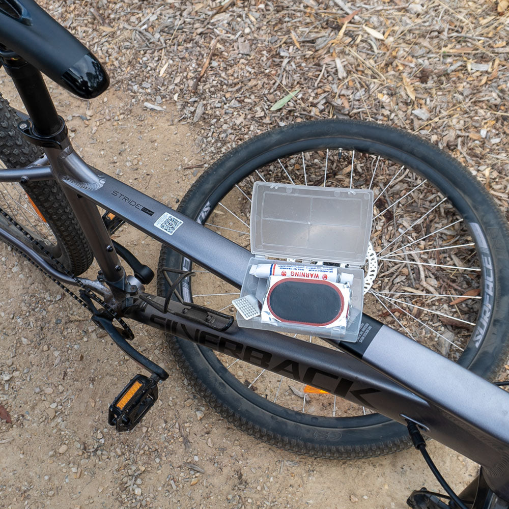 Cold patches kit with rubber cement and adhesive repair patches resting on rear wheel of a bicycle, ideal for fixing punctured bike tubes