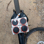 Cold patches kit with rubber cement and adhesive repair patches resting on rear wheel of a bicycle, ideal for fixing punctured bike tubes.
