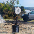 Folding spade in sand holding a toilet paper roll, with a tent and 4WD in the background.