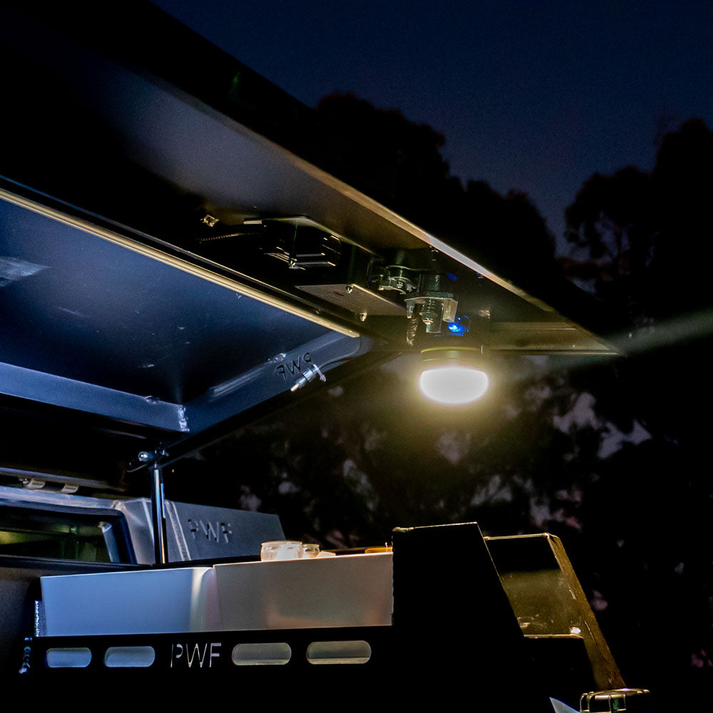 LED camping lantern mounted under canopy lid at night, providing bright overhead lighting for outdoor 4WD setup
