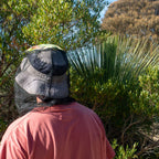 Person wearing mosquito fly net over hat while outdoors in bushland, ideal for insect protection during hiking or camping.