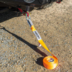 Orange snatch strap attached to 4WD recovery point on gravel surface
