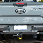 Black tow hitch receiver with mounted bow shackle and yellow isolator, attached to vehicle.