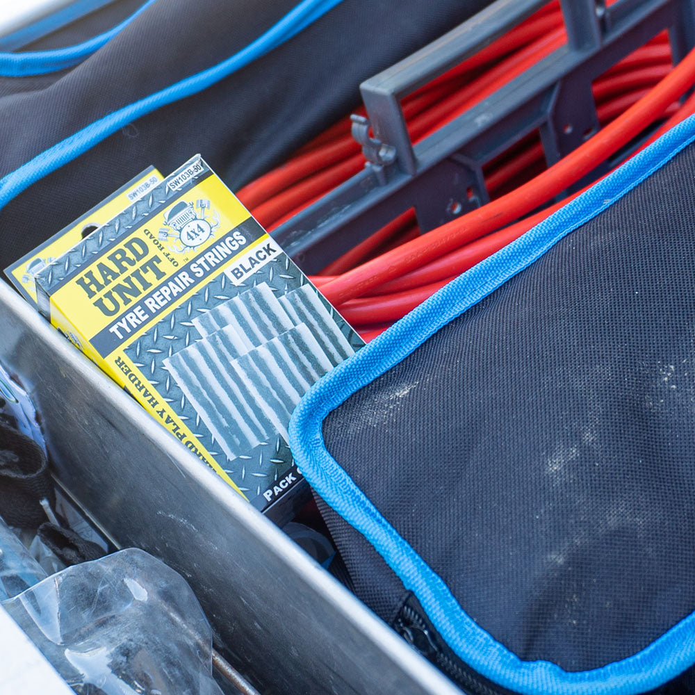 Box of Hard Unit tyre repair strings stored in a vehicle drawer system alongside jumper cables and tool bags.